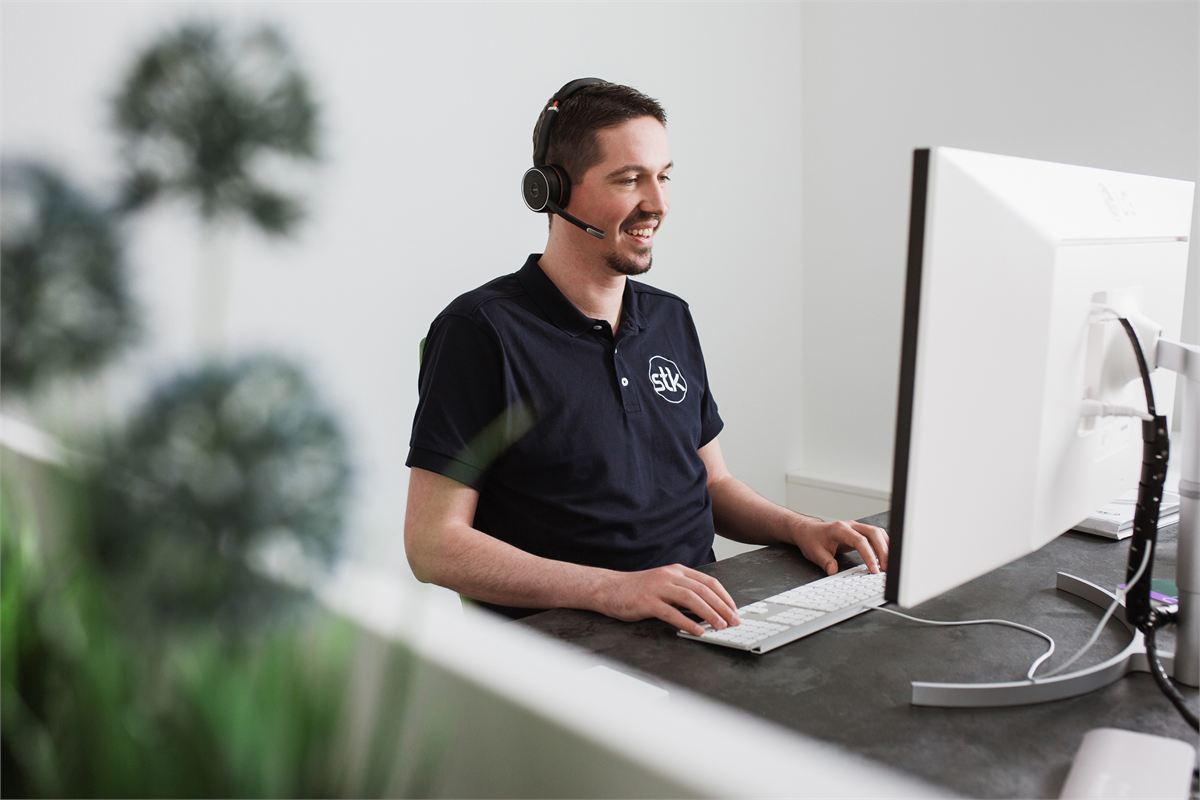 Ein Mitarbeiter im Kundenservice der STK AG mit Headset am Arbeitsplatz